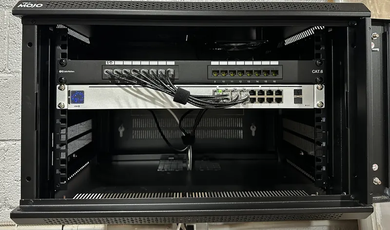 Wall-mount network rack at Chandler Park with a labeled Cat6 patch panel cabled into a UniFi 16-port PoE switch